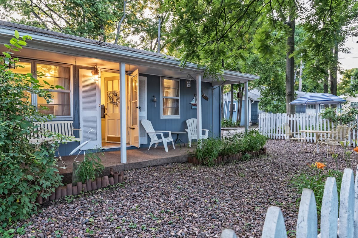 A house with a porch, white chairs, and a gravel driveway.