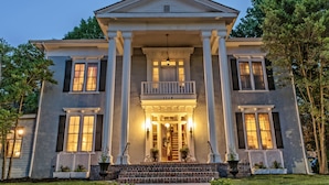 A stately two-story building with a central entrance, flanked by columns, and a balcony above the main door. - Silver Heart Inn and Cottages (Independence)