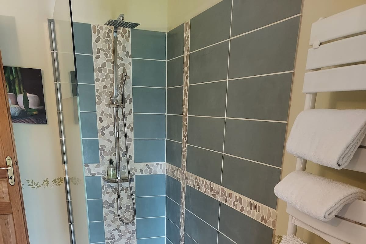 A bathroom with a shower area, tiled walls, and a towel rack.