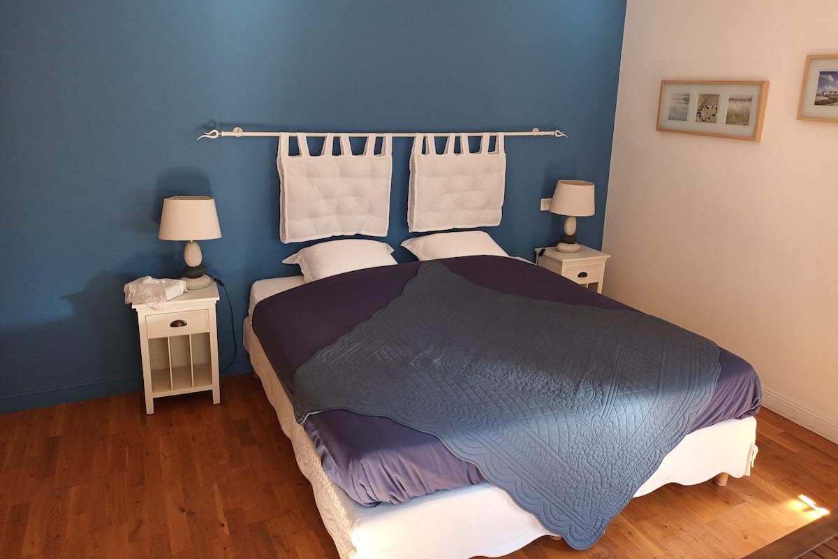 A bedroom with a bed, two bedside tables, a nightstand, and a headboard with a towel rack.