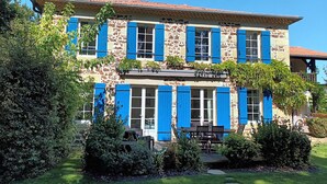 Un edificio de piedra de dos pisos con contraventanas azules y un balcón.