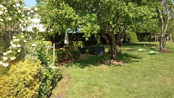 Een verzorgde tuin met diverse beplanting, een gazon en een schommel.