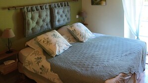Un dormitorio con una cama grande, paredes verdes y una viga de madera en el techo.