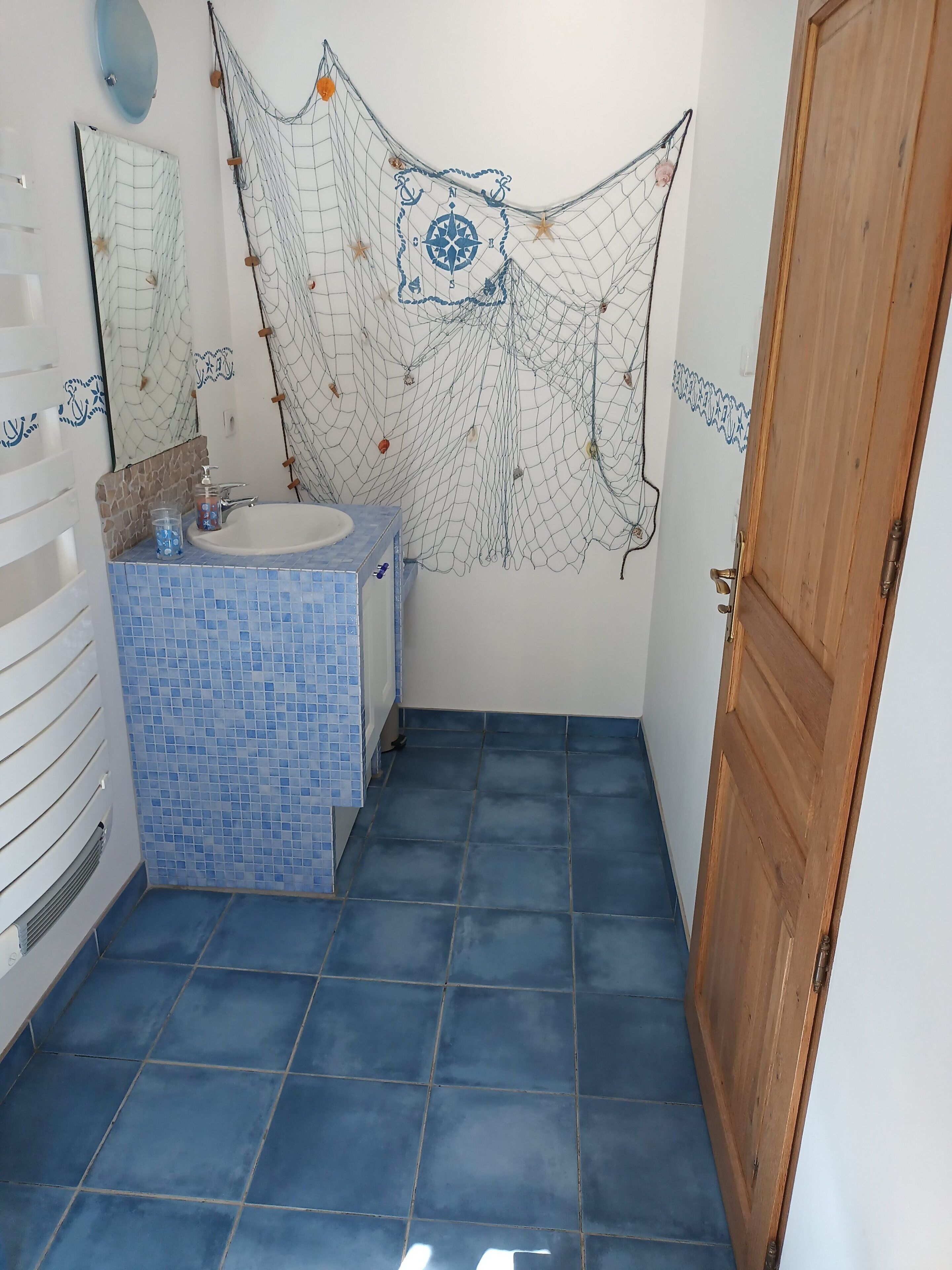 Un baño con piso de baldosas, lavamanos y espejo.