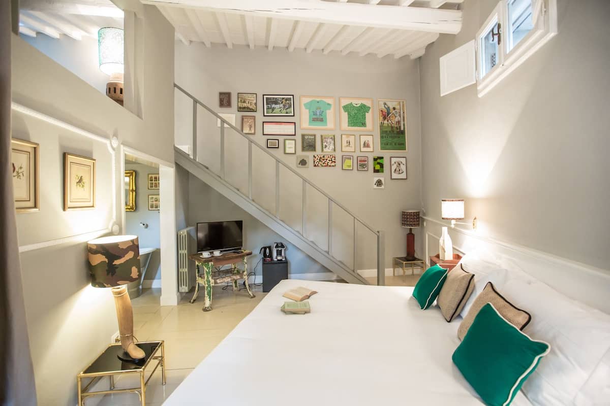A hotel room with a bed, a staircase, and a wall decorated with framed pictures.