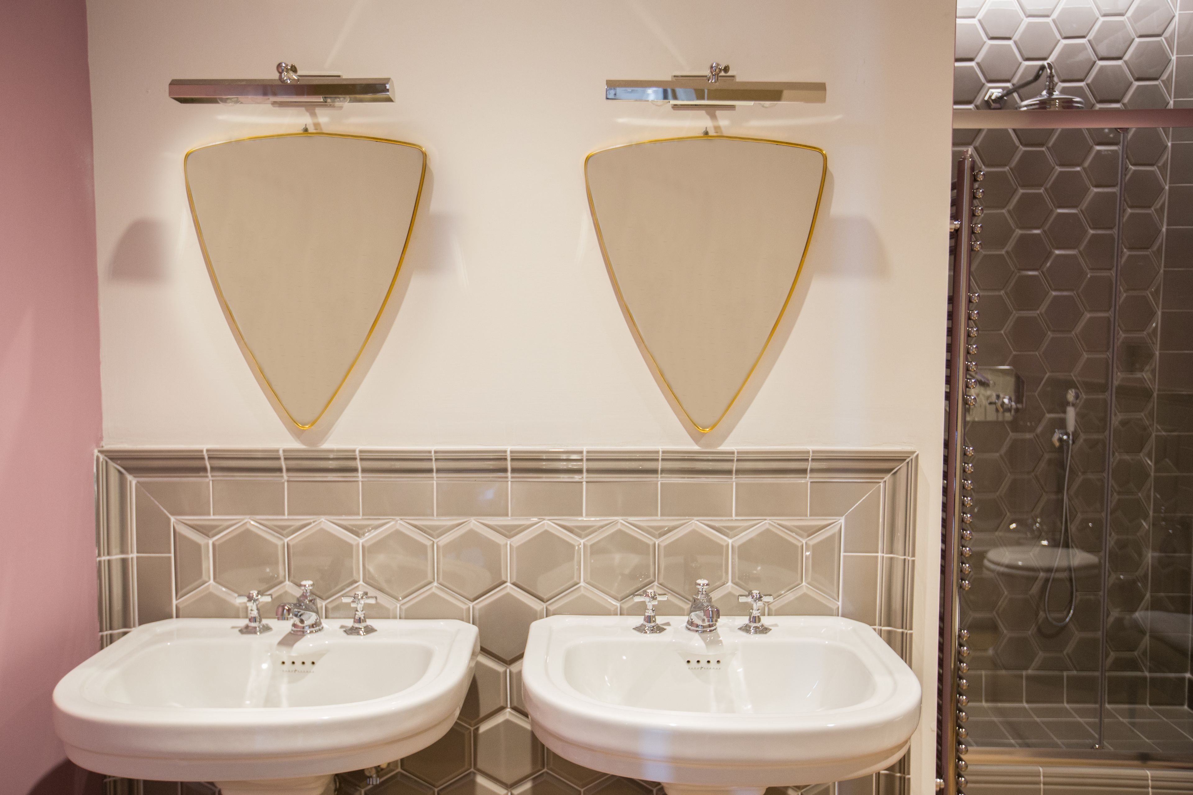 A bathroom with two sinks, a mirror, and a shower area.