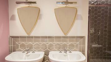 A bathroom with two sinks, a mirror, and a shower area.