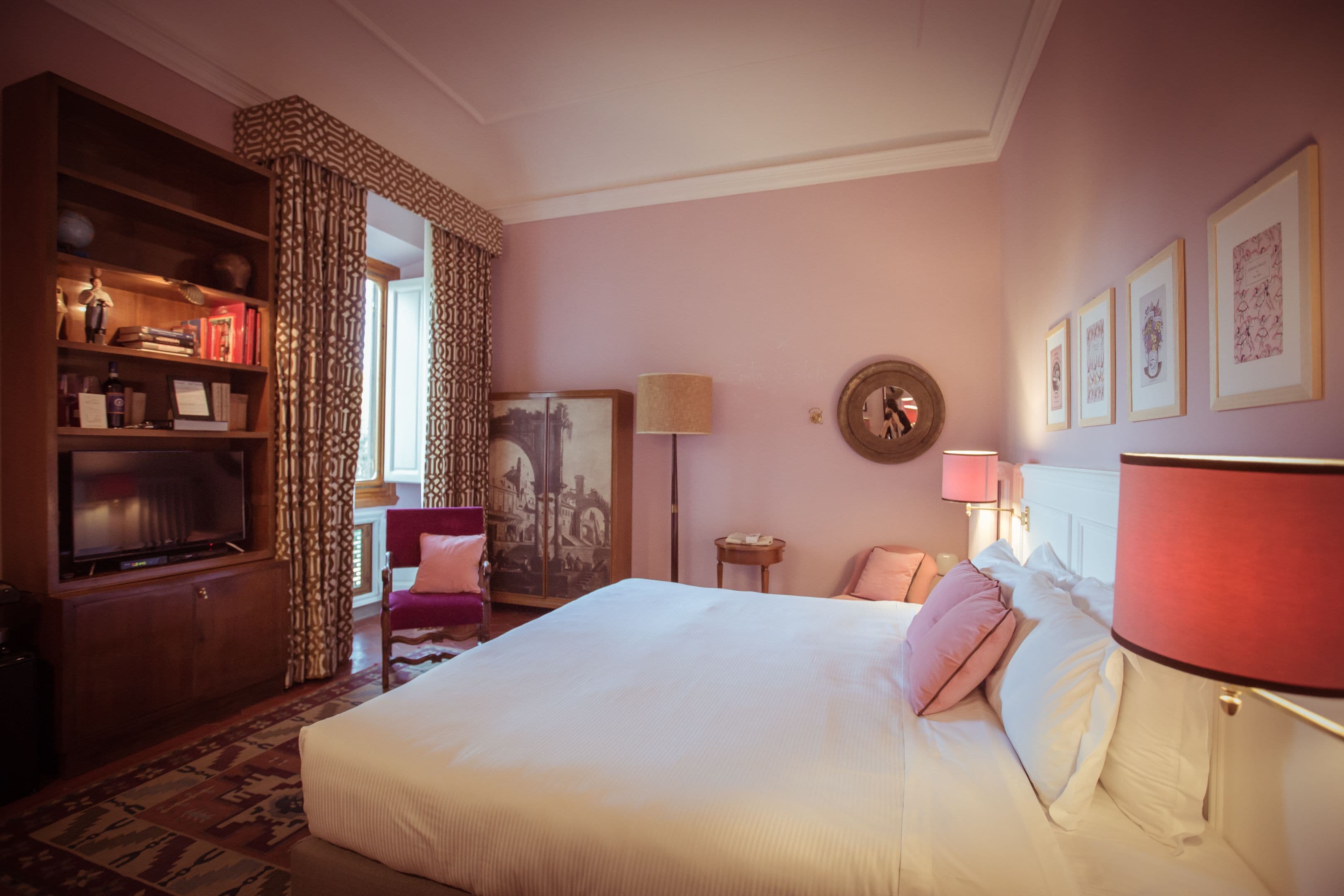 A hotel room with a large bed, a wooden wardrobe, a desk, and a chair.
