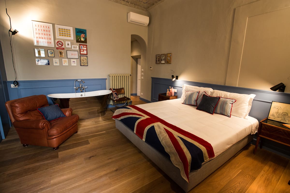 A bedroom with a large bed, a chair, a small table, and a radiator.