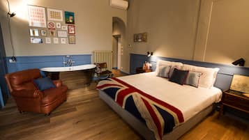 A bedroom with a large bed, a chair, a small table, and a radiator.