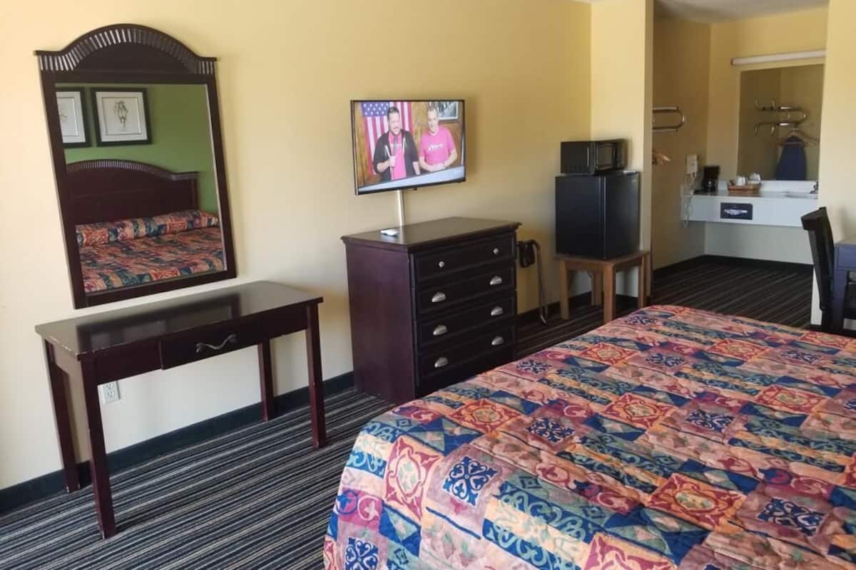 Hotellihuone, jossa on sänky, työpöytä, lipasto, televisio ja mikroaaltouuni.