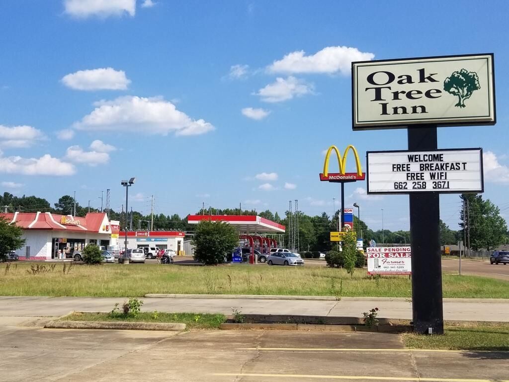 A sign for Oak Tree Inn with amenities including free breakfast and free WiFi.
