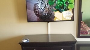 A television mounted on a wall displaying a decorative item and a potted plant.