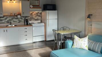 A compact living space with a kitchenette, a dining area, and a seating area with a sofa and a table.