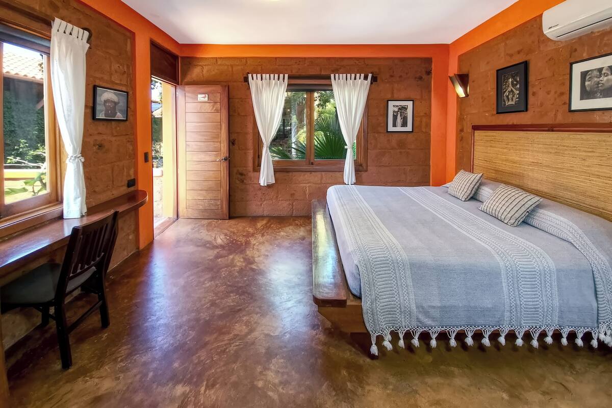 A room with a bed, a desk, and a window with curtains.