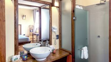 A bathroom with two large sinks, a mirror, a towel rack, and a shower area.