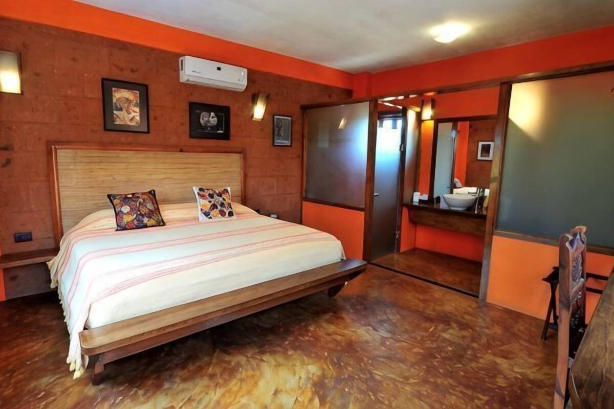 A bedroom with a wooden bed, a mirror, and a red wall.