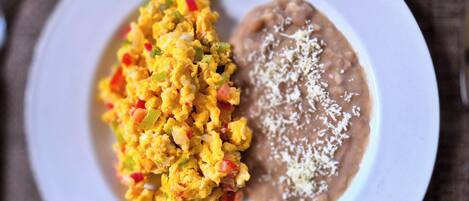 A plate with scrambled eggs and refried beans.