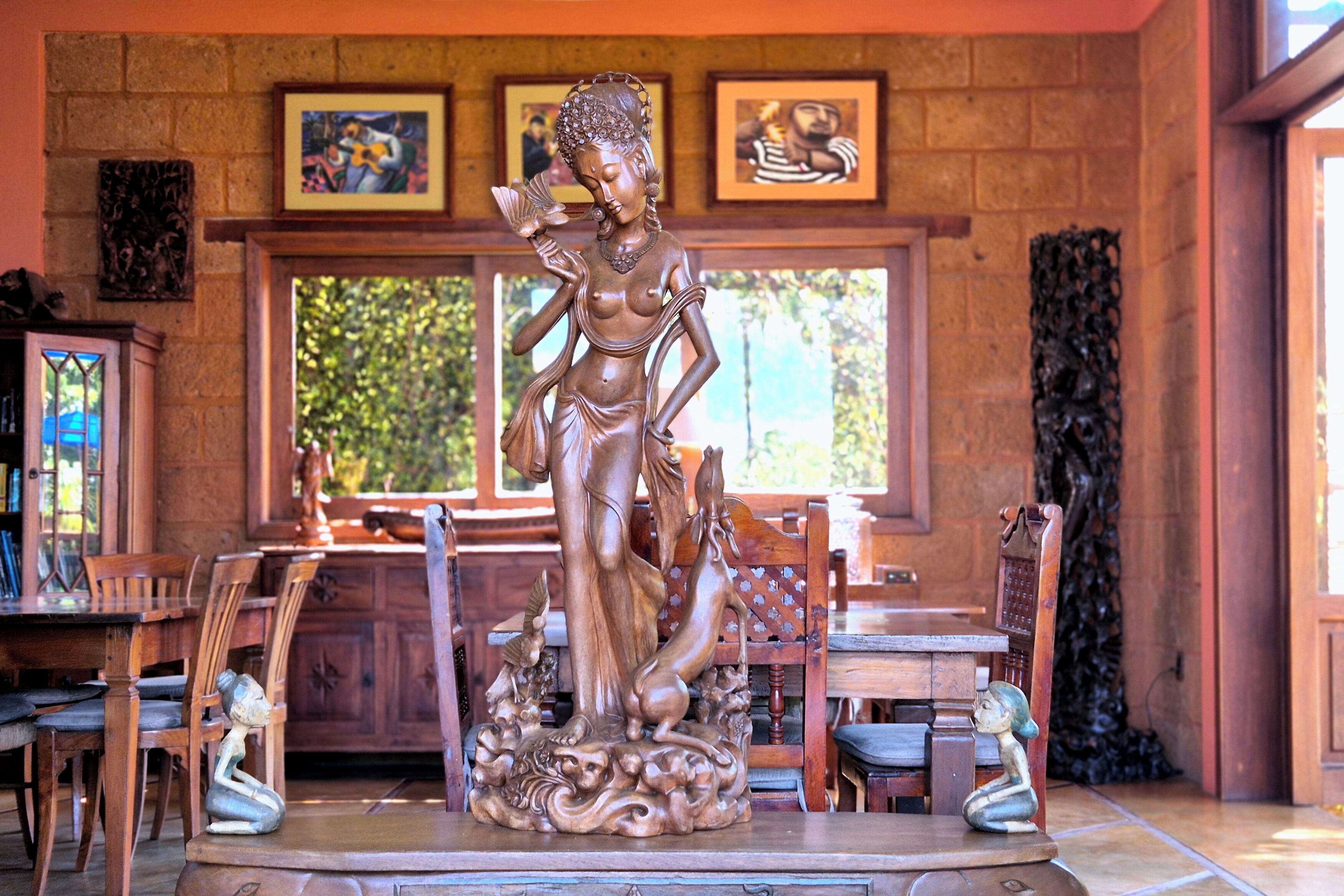 Eine Statue einer Frau in einem Raum mit Holzmöbeln und gerahmten Bildern an der Wand.