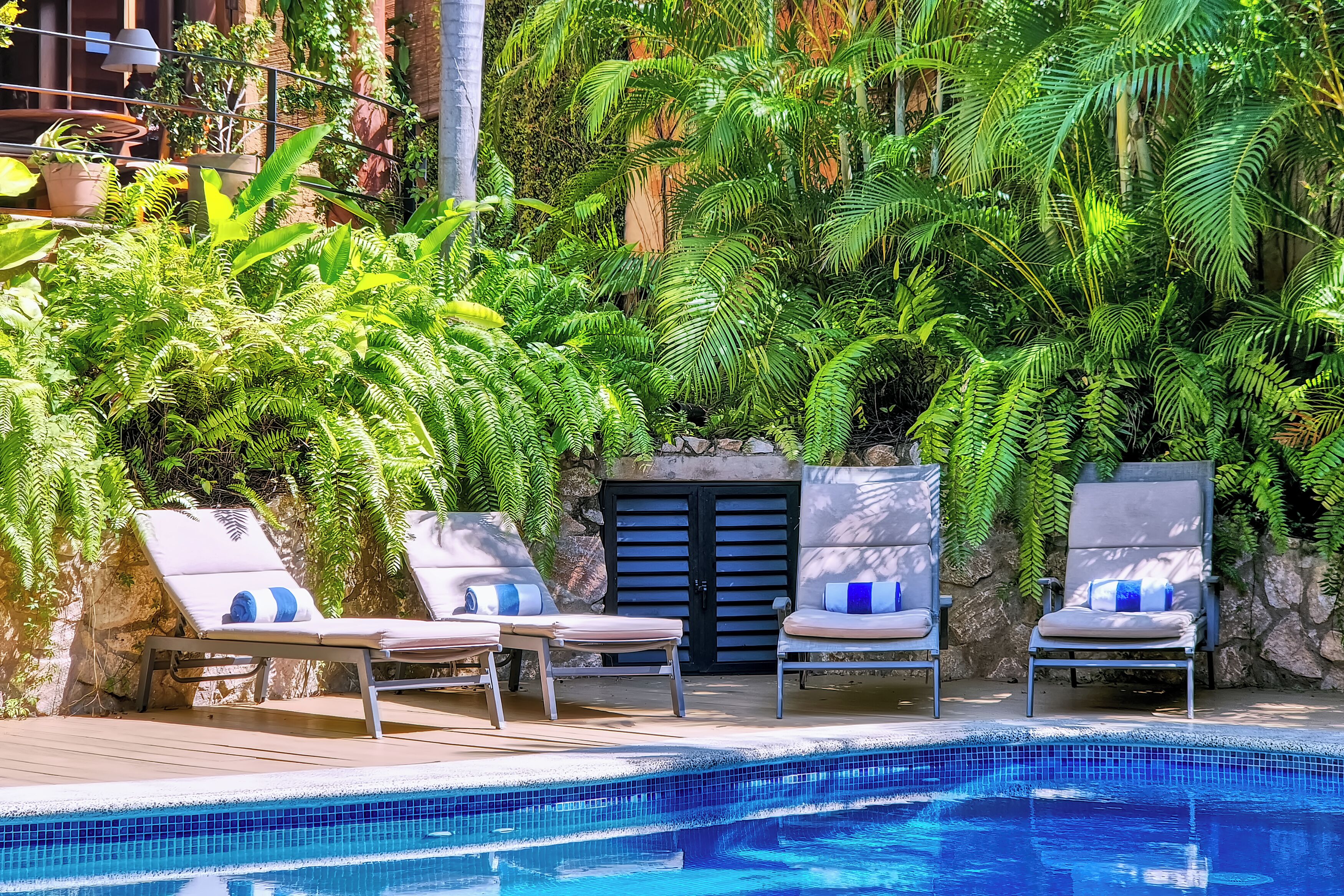 Un área junto a la piscina con sillones de descanso y una piscina azulejada.