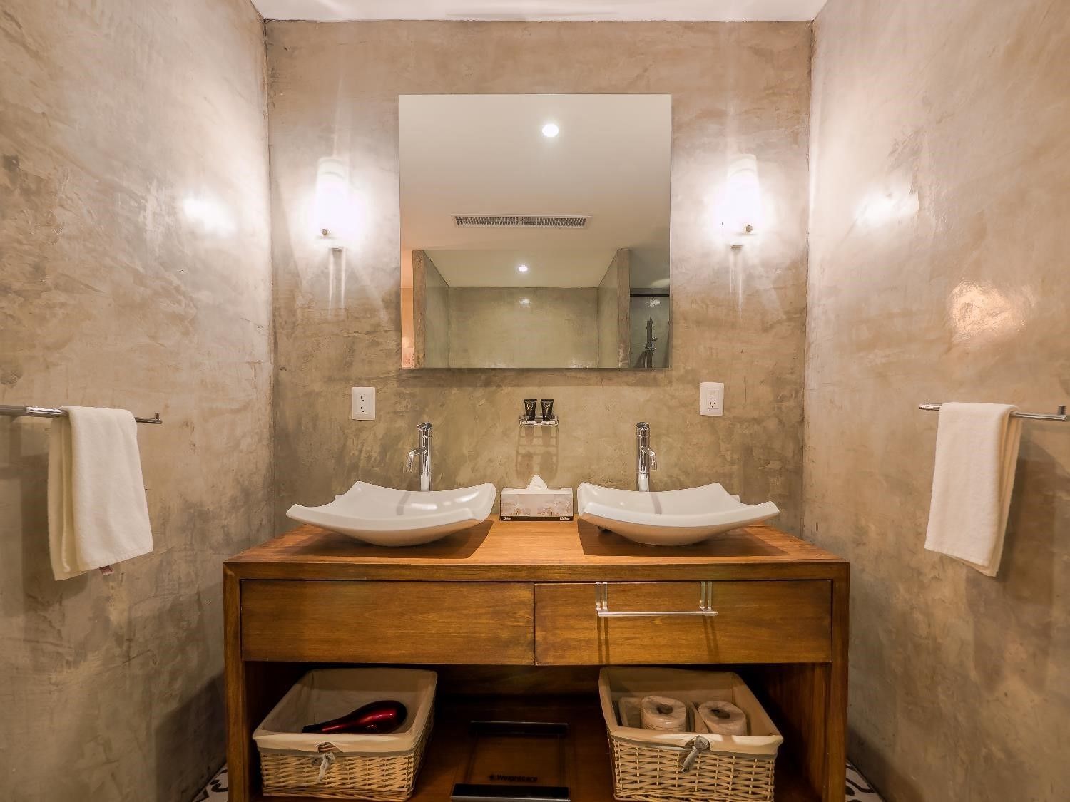 A bathroom with two sinks, a mirror, and two wall-mounted lights.