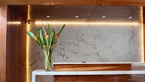 A reception desk with a marble countertop and wooden paneling. - Habitat Hotel (Lima)