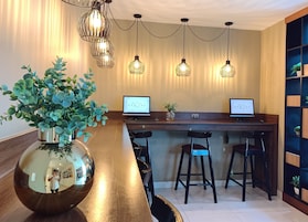 Una moderna hall d'hotel con una reception in legno, due monitor per computer e un grande specchio.