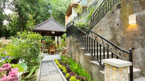 A stone staircase with a black railing leading to a wooden structure with a tiled roof. - Villa Bakti Ubud (Ubud)