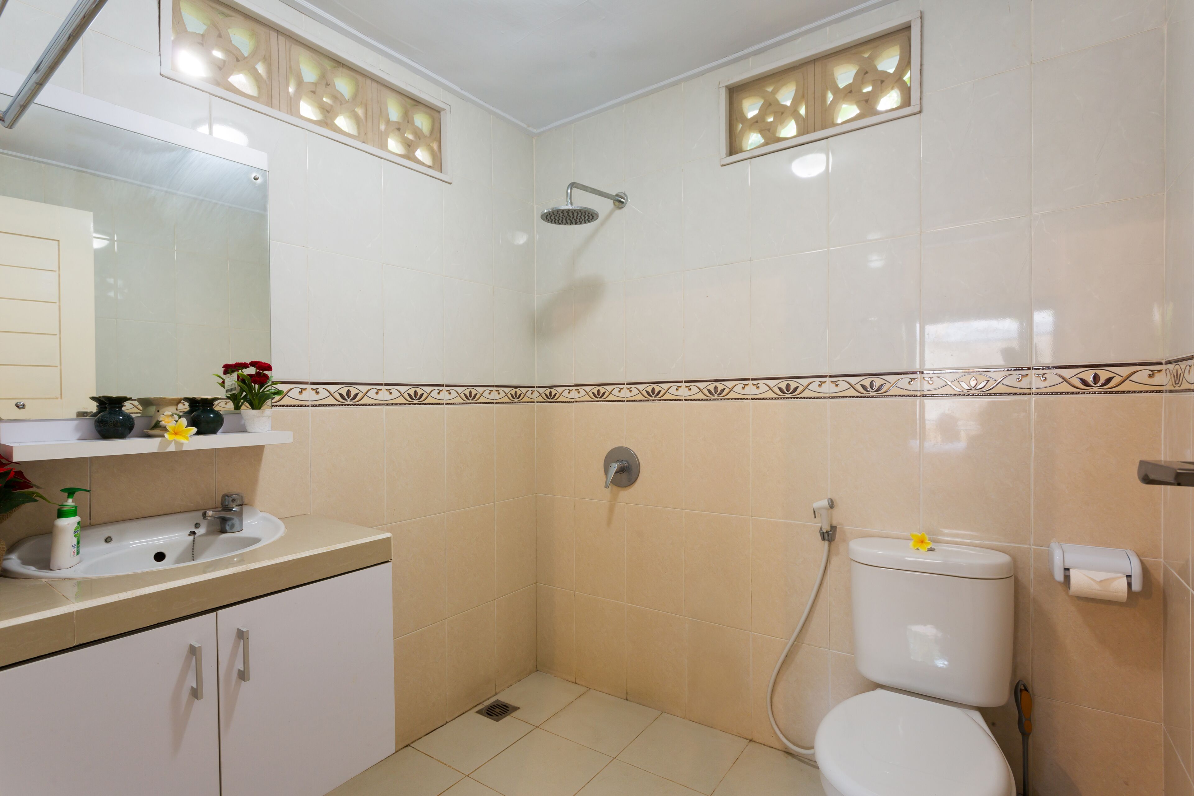 Casa de banho com lavatório, sanita e chuveiro, decorada com azulejos.