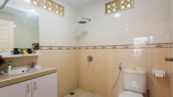 Casa de banho com lavatório, sanita e chuveiro, decorada com azulejos.
