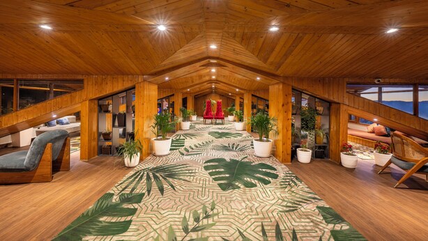 A spacious attic room with wooden beams, a central red chair, potted plants, and a patterned carpet. - Snow Valley Resorts (Shimla)
