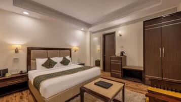 Ein Hotelzimmer mit einem großen Bett, Nachttischen, einem Kleiderschrank und einem kleinen Tisch.