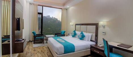 A hotel room with a large bed, a desk, a chair, and a TV.