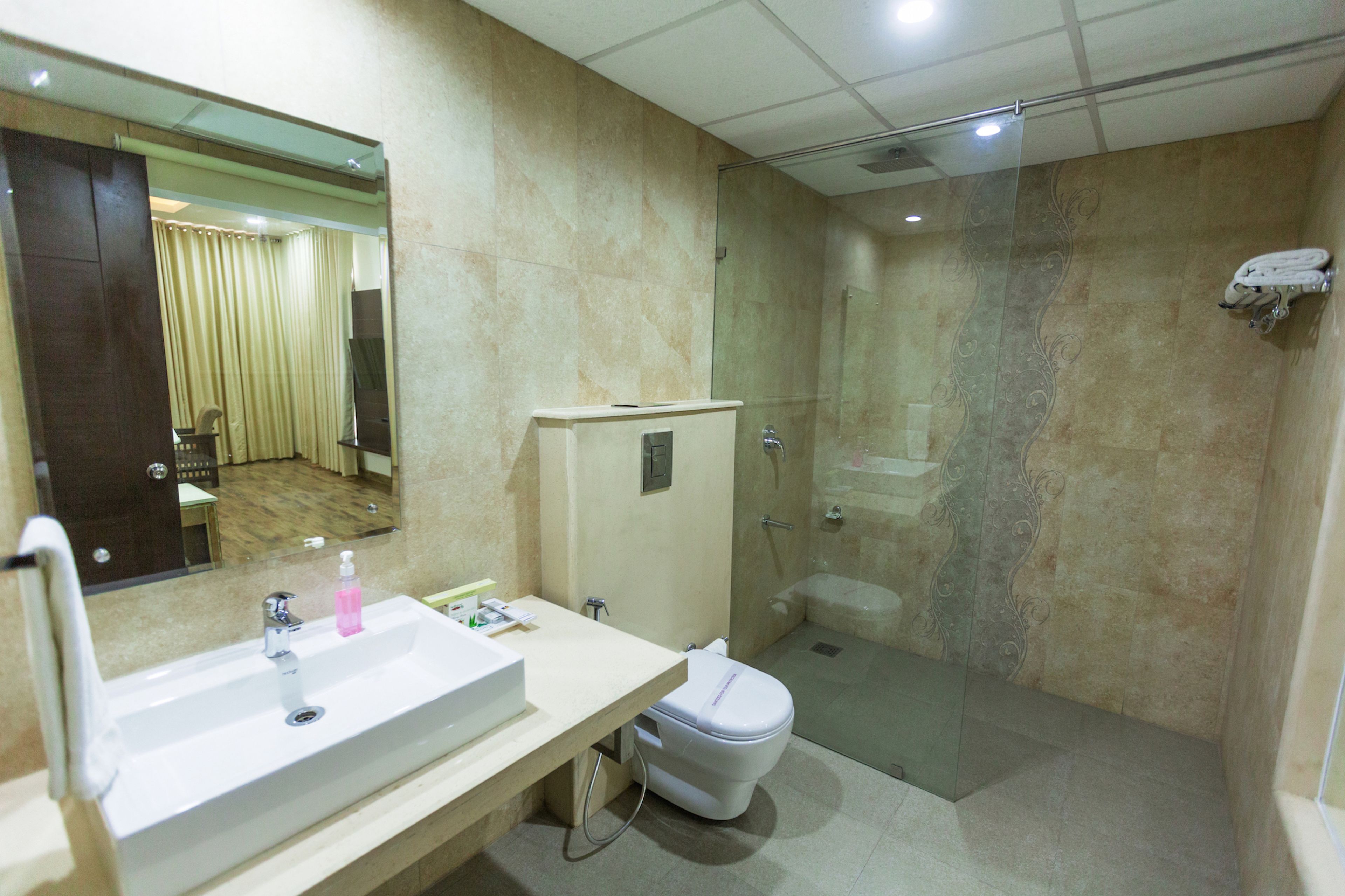 A bathroom with a sink, mirror, toilet, and glass-enclosed shower.