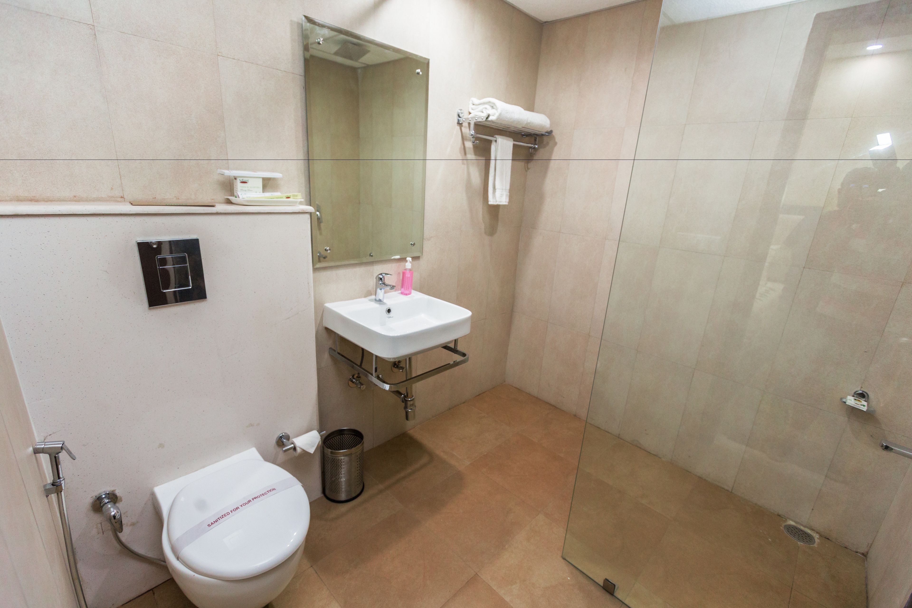 Une salle de bain équipée de toilettes, d’un lavabo, d’un miroir et d’une douche.