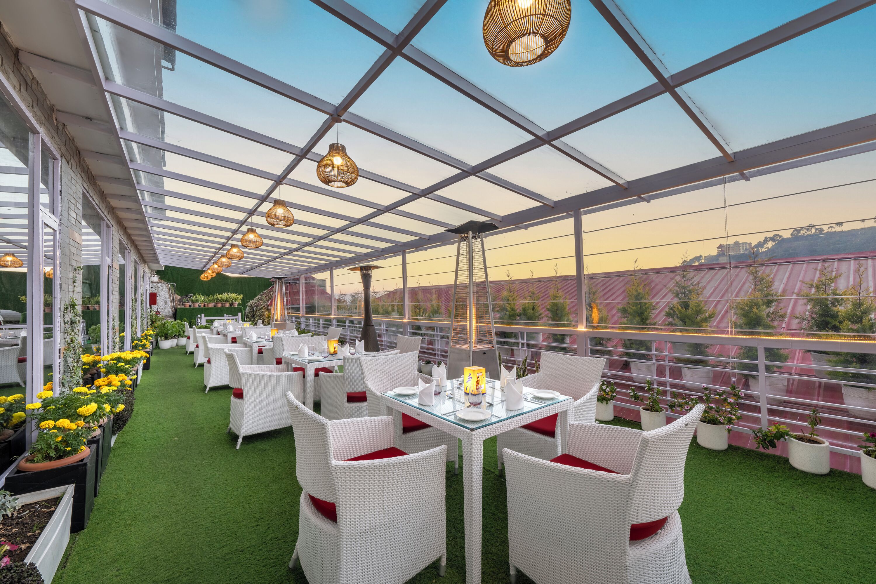 An outdoor dining area with white wicker furniture, green artificial turf, and potted plants.