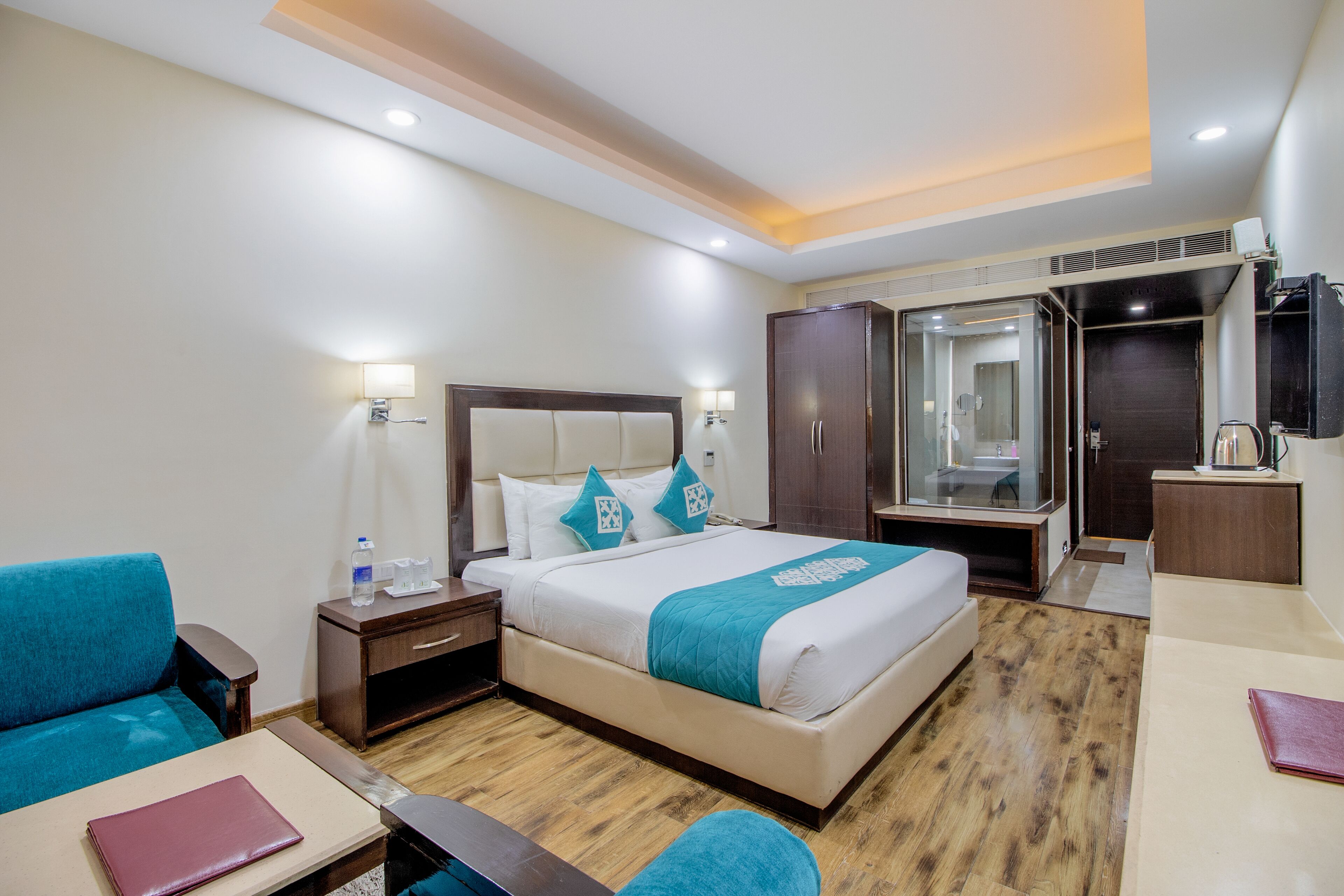Una habitación de hotel con cama, escritorio, silla, armario y baño.