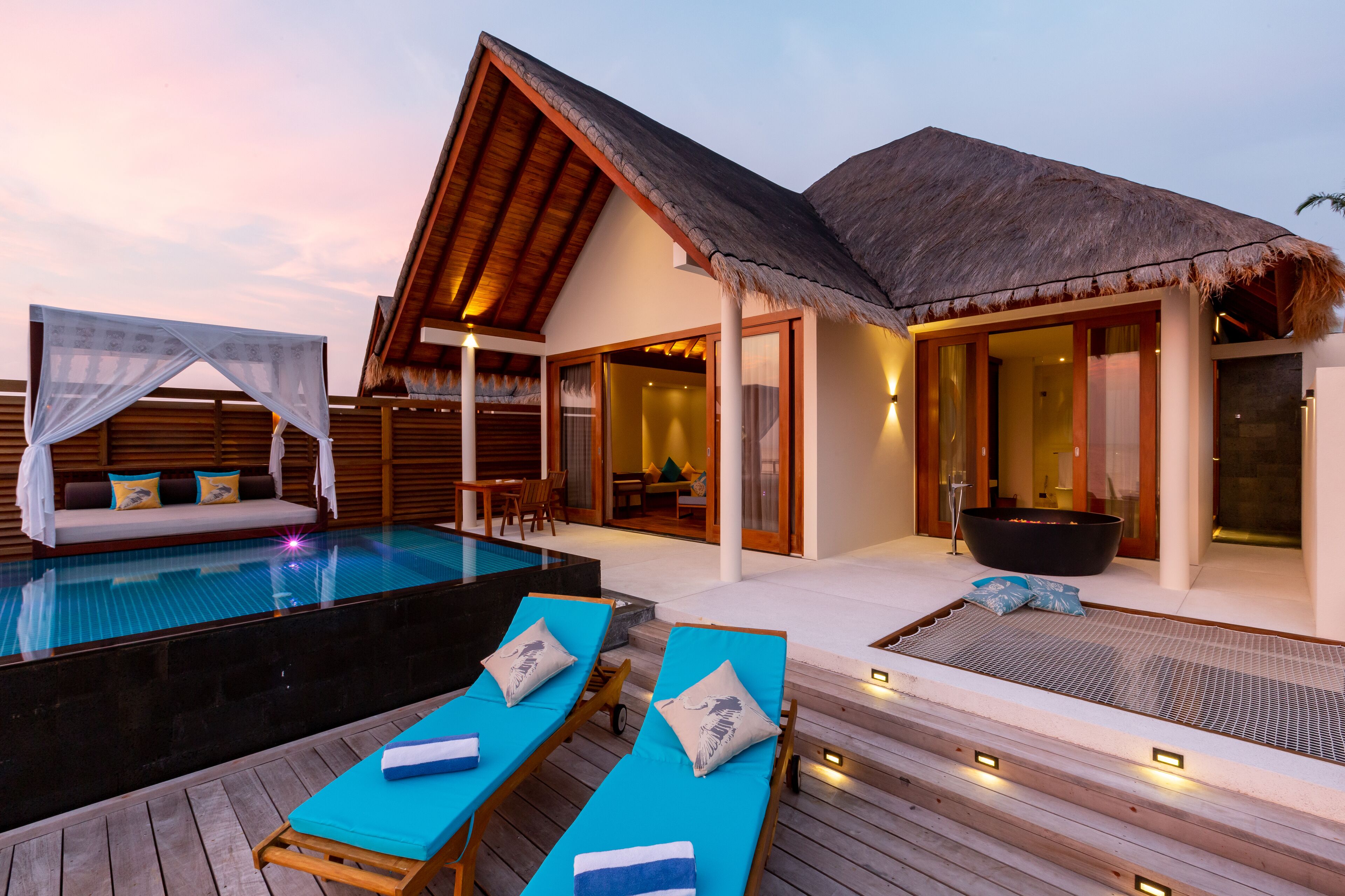 An infinity pool with lounge chairs, a thatched-roof structure, and a spa area.