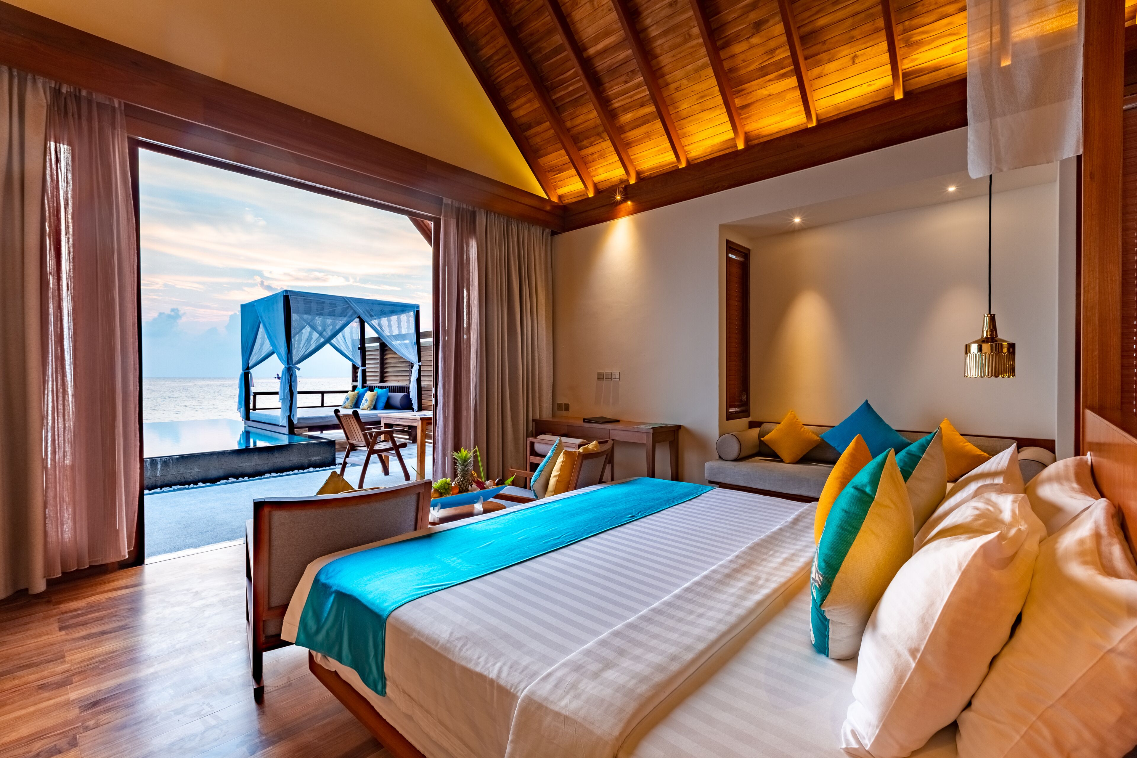 Een hotelkamer met een groot bed, een bureau en uitzicht op de oceaan.
