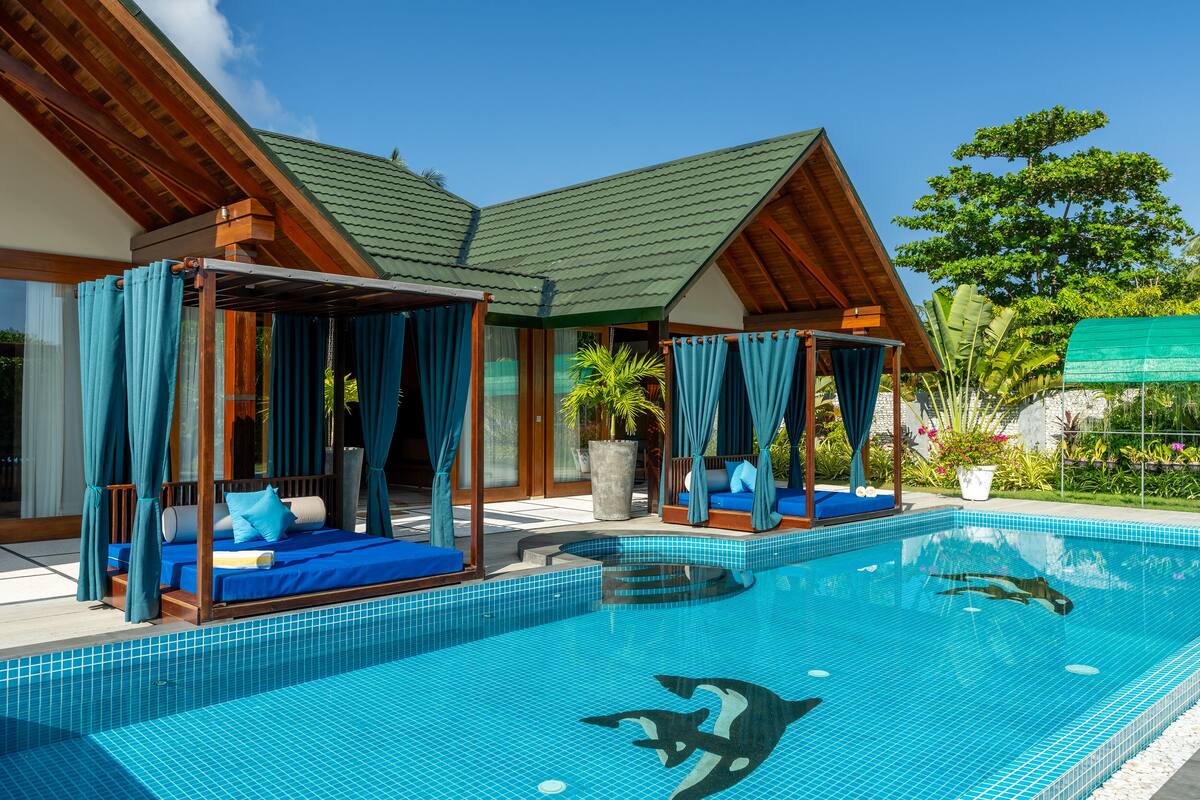 A poolside area with a bed, a covered seating area, and a view of the pool.