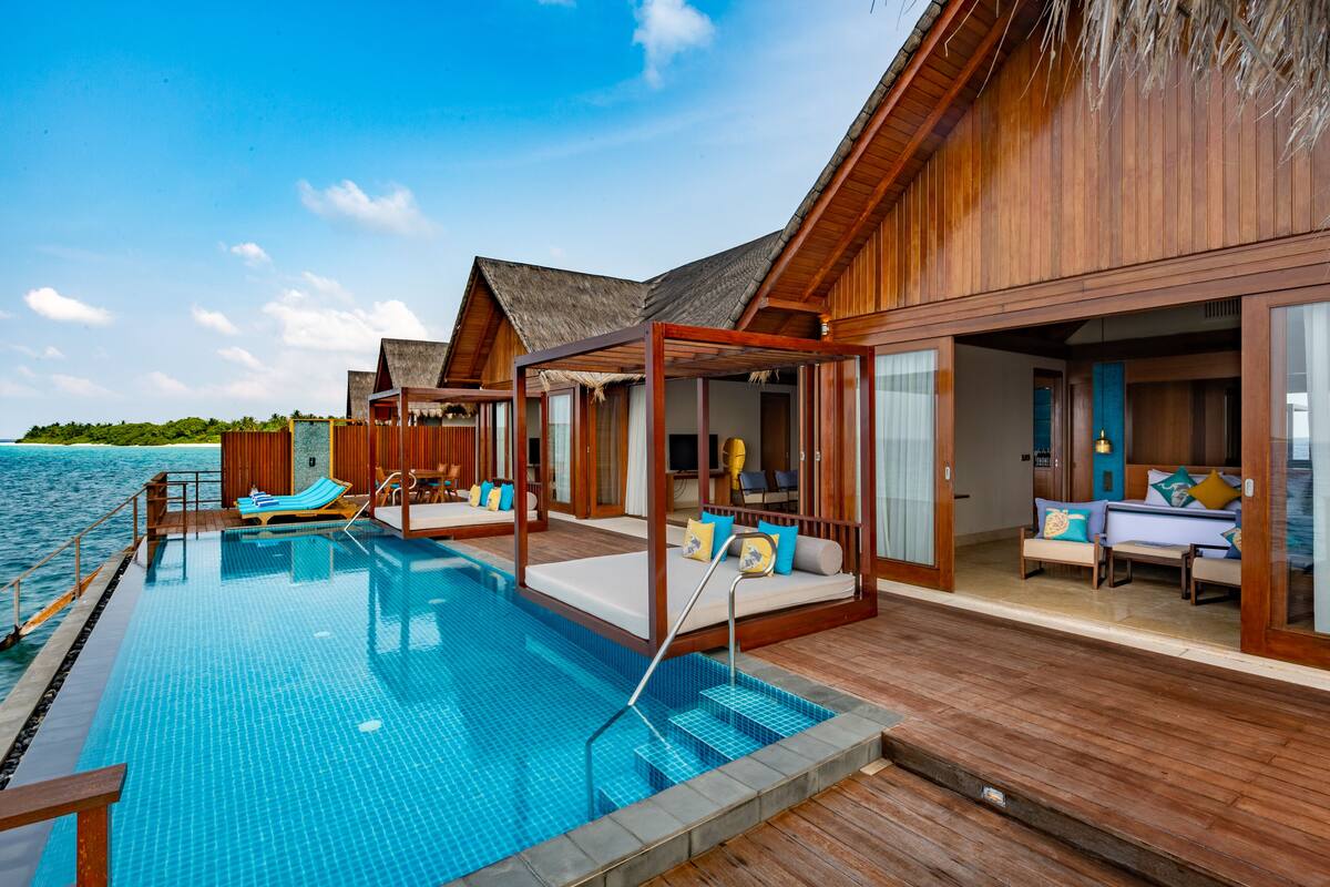An overwater villa with a pool, wooden deck, and ocean view.
