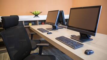 A workspace with three computer monitors, a keyboard, and a mouse on a wooden desk.