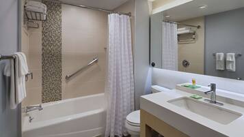 A modern bathroom with a bathtub, shower, toilet, and a vanity with a sink and mirror.