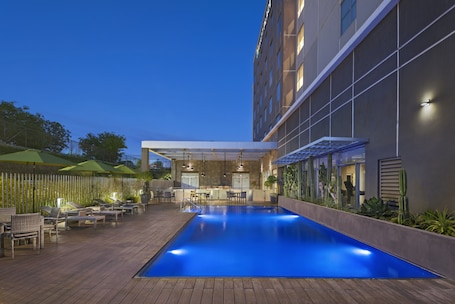 Una piscina al aire libre, sillones reclinables de piscina