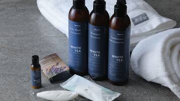 A set of Westin toiletries including body wash, shampoo, conditioner, and a body lotion, along with a white towel and a small bottle of white tea.