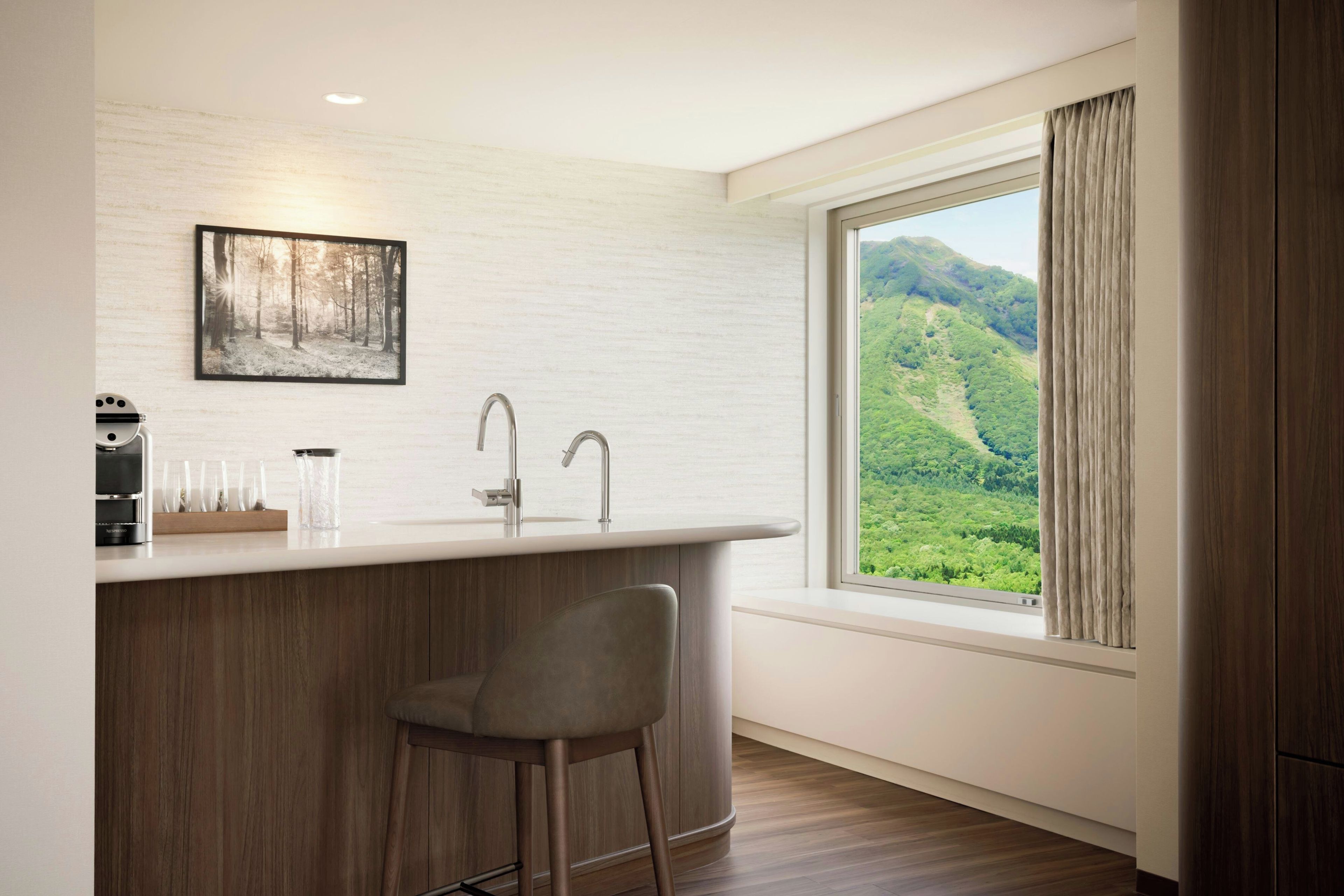 A modern kitchen with a bar area, a sink, and a window with a view of a green landscape.