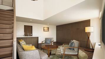 A modern living room with a staircase, a round wooden coffee table, and a sofa with patterned cushions.