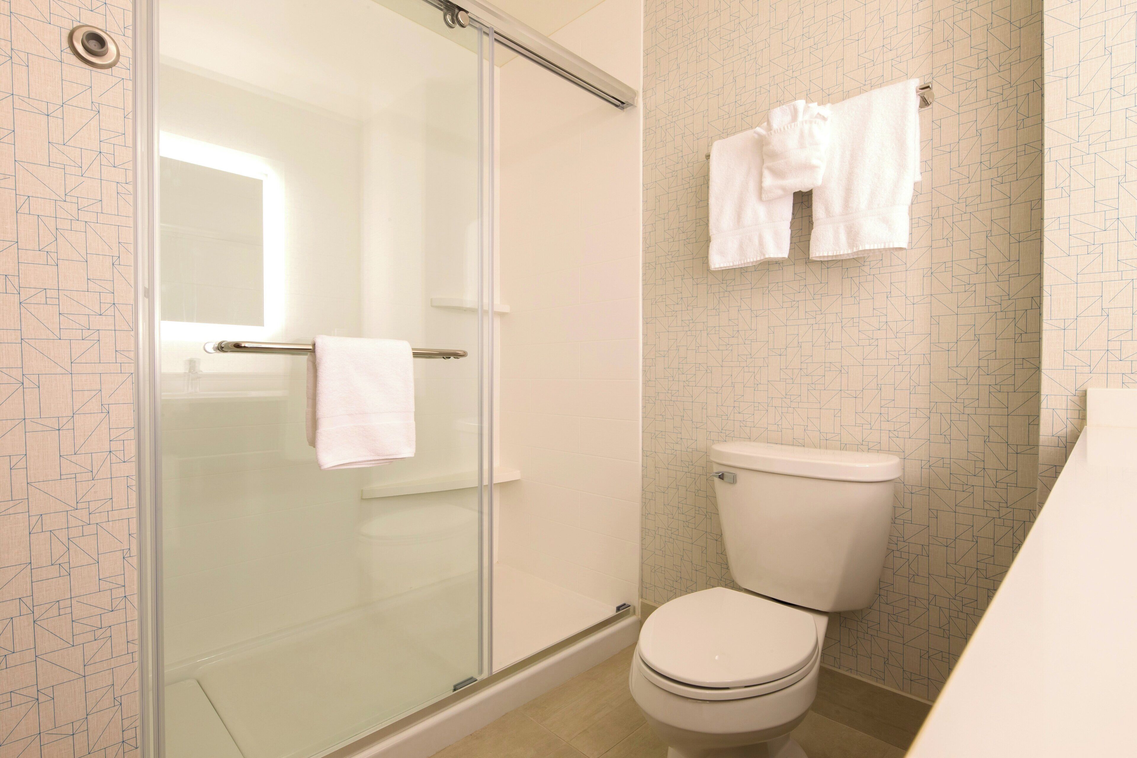 Ein Badezimmer mit Duschkabine, Toilette und Handtuchhalter mit Handtüchern.