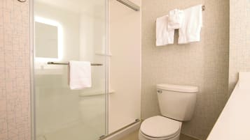 Ein Badezimmer mit Duschkabine, Toilette und Handtuchhalter mit Handtüchern.