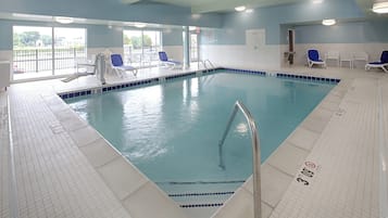 Una piscina techada, sillones reclinables de piscina